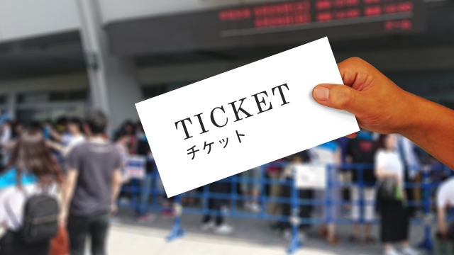 イベント会場前でチケットを手にもってかざしている人
